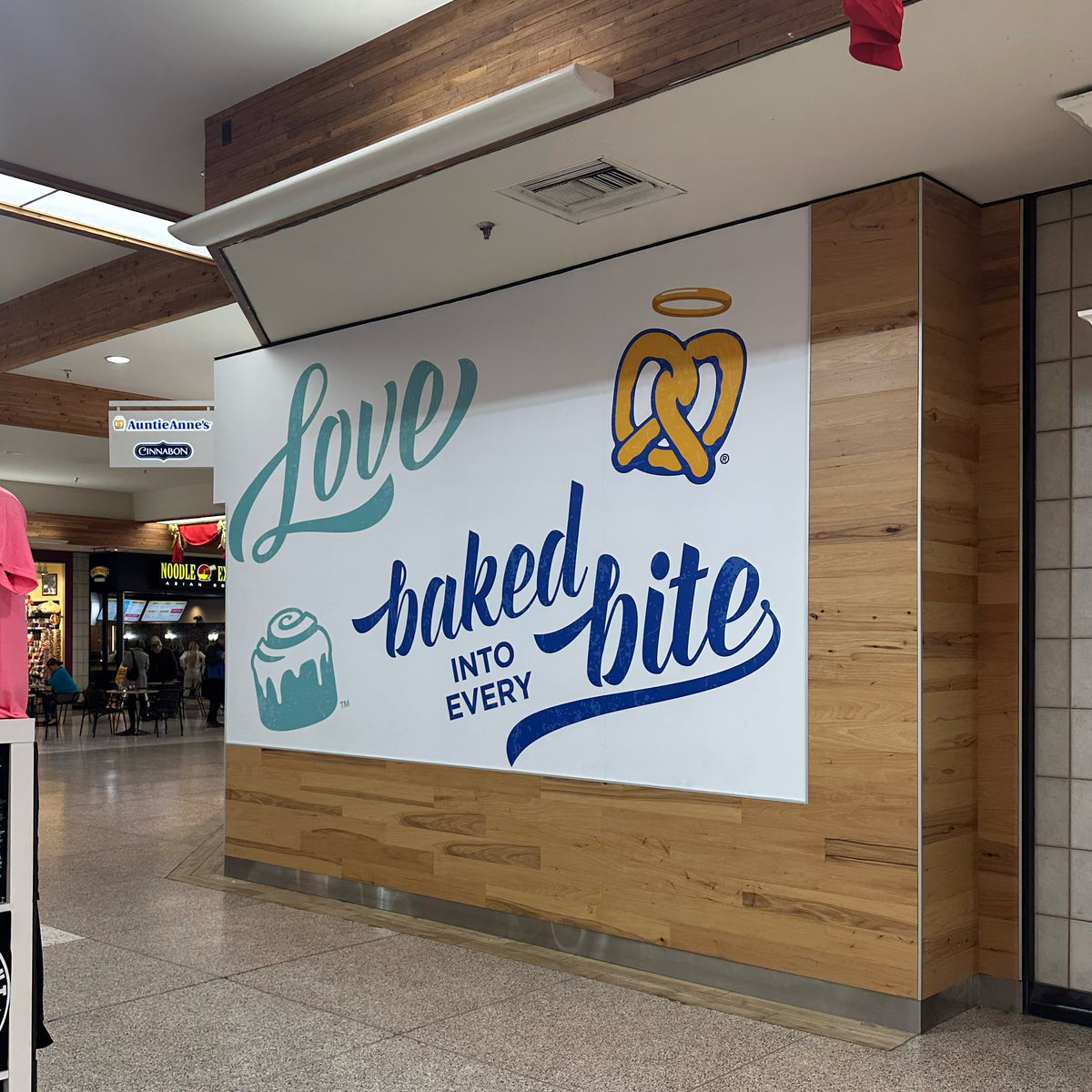 Auntie Anne's custom printed wall graphic installed on a wall in a crowded area of the mall. 