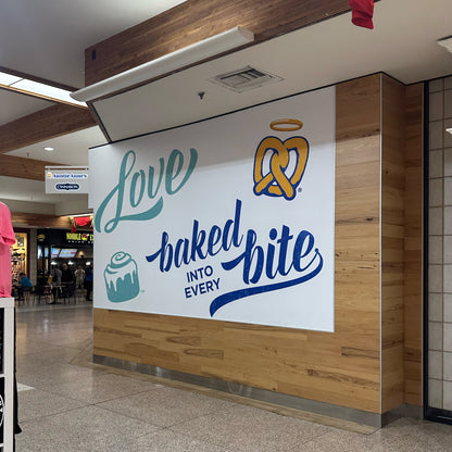 Auntie Anne's custom printed wall graphic installed on a wall in a crowded area of the mall. 