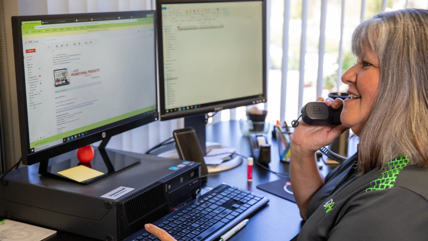 A woman speaking on the phone while working on the computer for 760 Print.
