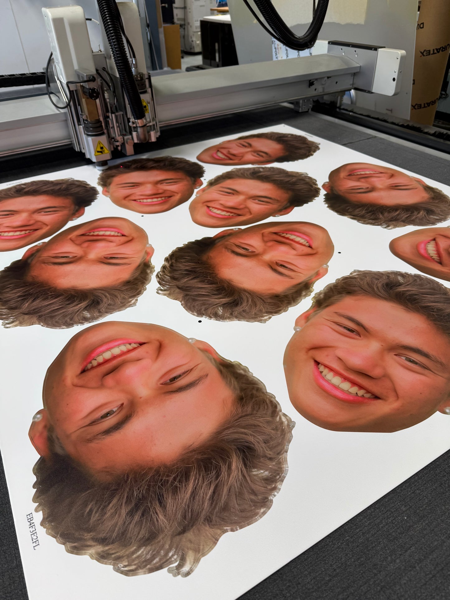 Custom coroplast head cutouts of a smiling person's face being produced on a flatbed printer by 760 Print in Vista.