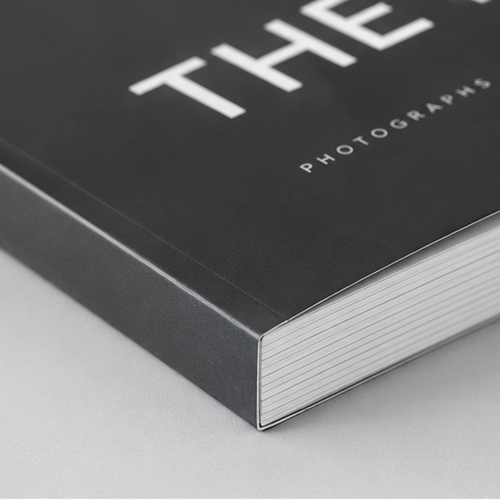 Close-up detail of a custom printed black softcover book spine and perfect bound edges for 'The Photographs', showcasing high-quality commercial book binding by 760 Print in Vista.