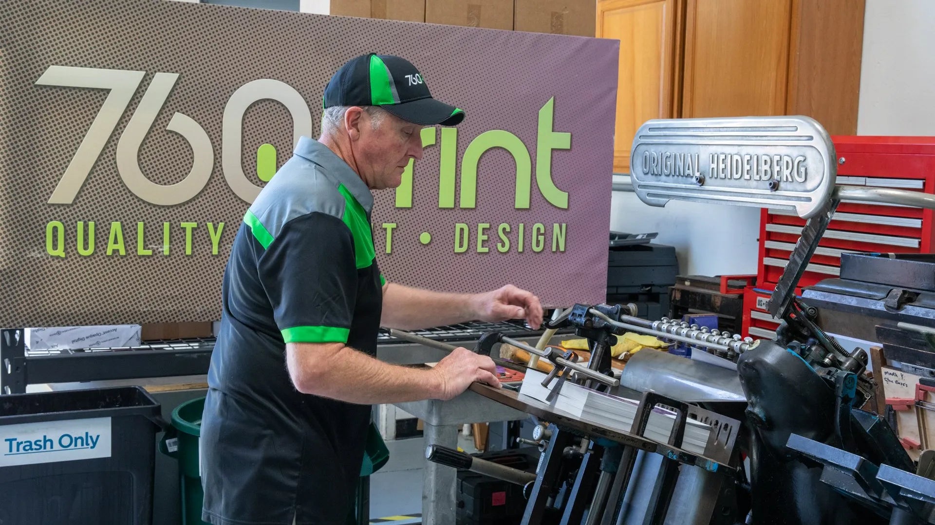 Man using the Original Heidelberg to cut packaging to size in print shop with 760 Print logo in background.