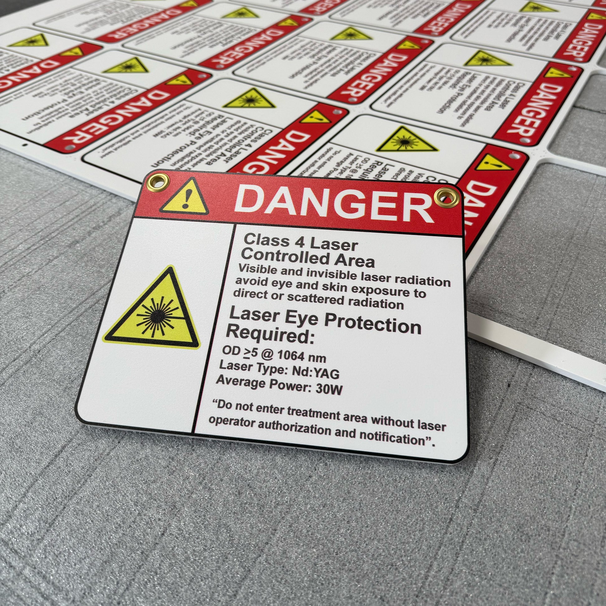 A stack of custom PVC Sintra board prints with a danger sign warning of a class 4 laser area, indicating the need for laser eye protection.